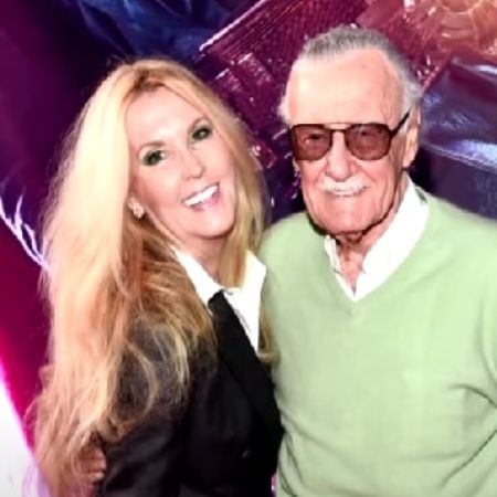 Stan Lee and Joan Celia Lee are smiling and posing in the red carpet.